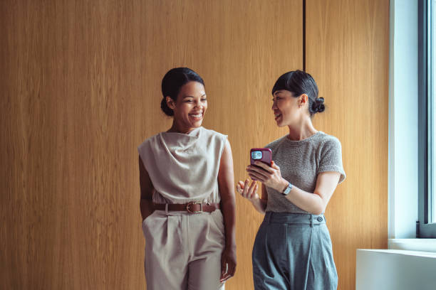 Businesswomen Engaging in Friendly Conversation With Smartphone