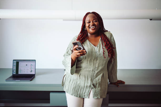 Confident Businesswoman Smiling and Using Smartphone in Office