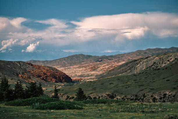 Brightly lit mountain landscape with red rock on midground