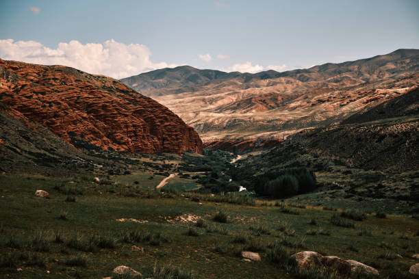 Brightly lit mountain landscape with red rock on midground