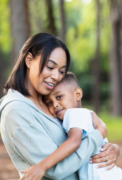 istock Multiracial young mother smiles, hugging son at the park 2161898811