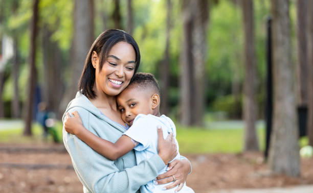 istock Multiracial young mother smiles, hugging son at the park 2161898813