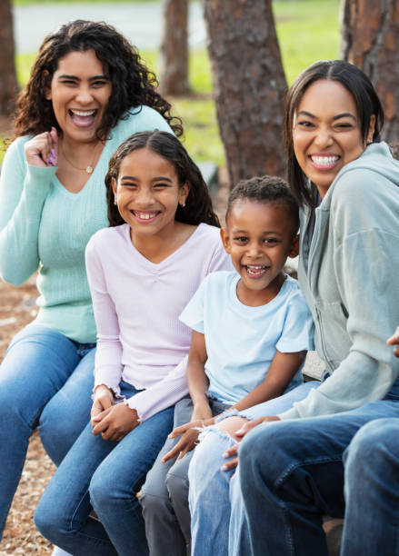 istock Two multiracial mothers, children sitting on park bench 2161898835