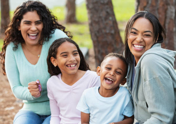 istock Two multiracial mothers, children sitting on park bench 2161898836