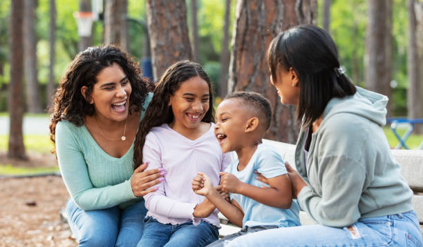 istock Two multiracial mothers, children laughing on park bench 2161898837