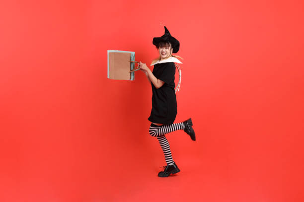 A charming  witch  with a carved pumpkin  and magic pot with smoke on Halloween night