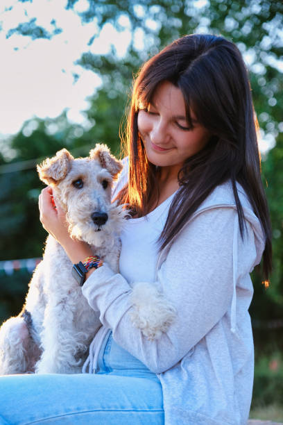 istock Smiling woman holding Fox Terrier in sunset light 2161900439