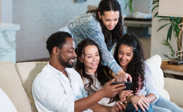 istock Multiracial family on sofa looking at mobile phone 2161903055