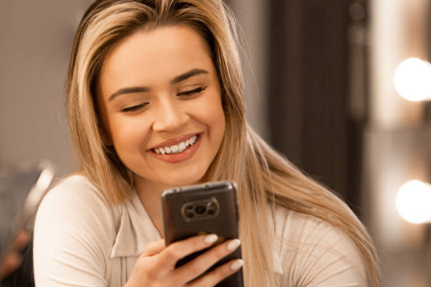 istock Smiling Beautiful Girl Typing on Phone in modern home interior 2161908691