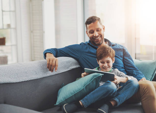 Happy, tablet and dad with child on sofa for online streaming, playing games and internet. Family, home and father with young boy on digital tech for watching movies, cartoons and videos for bonding Learning in a fun way 4k gaming stock pictures, royalty-free photos & images