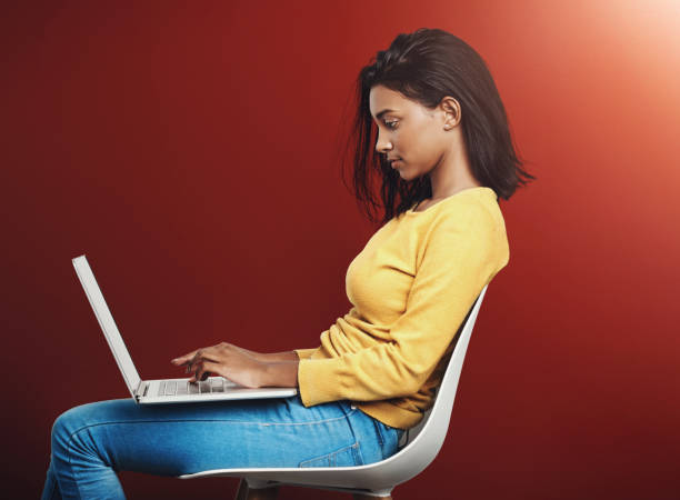istock Typing, chair and woman with laptop in studio for school project, knowledge or browsing internet on red background. Profile, student and Indian person for education, history paper or learning mockup 2161914631