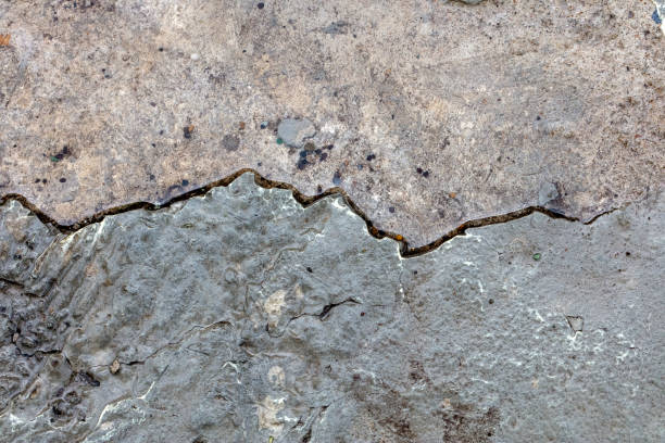 A high resolution old concrete cement with cracks and natural destruction from time and weather conditions. Non-color, monochrome black and white photo.