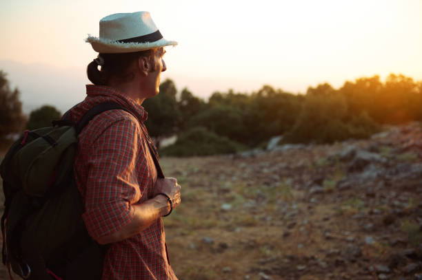 istock A man wearing a hat and backpack hikes through a scenic landscape during sunset 2161920295
