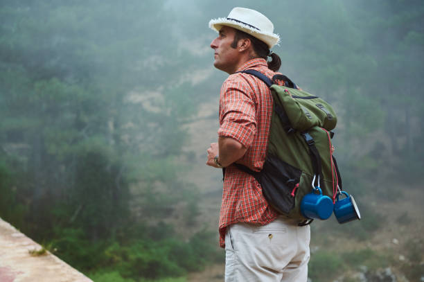 istock Man hiking in misty forest wearing a backpack and hat 2161921025