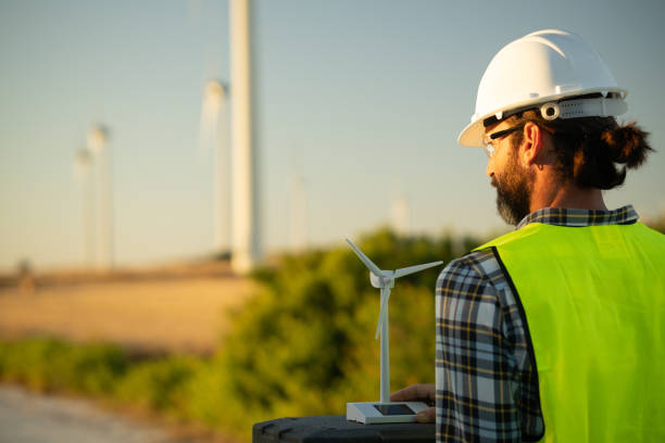 istock Engineer holding small wind turbine model analyzing wind farm for sustainable energy generation 2161922938