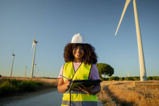 istock Young female engineer is working on a wind turbine farm and taking notes on a digital tablet 2161922965
