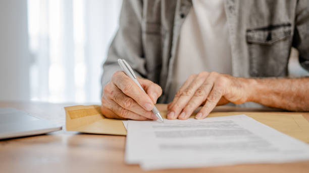 istock senior caucasian man open mail letter sign contract document at home 2161926104