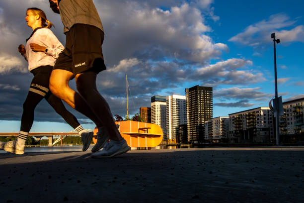 Stockholm, Sweden June 10, 2024 A man and a woman jogging at sunset in the Liljehomlmskajen district.
