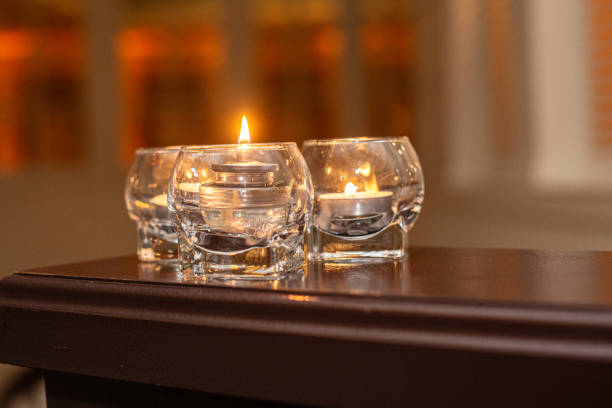 Three glass lit candles on wood table with warm background
