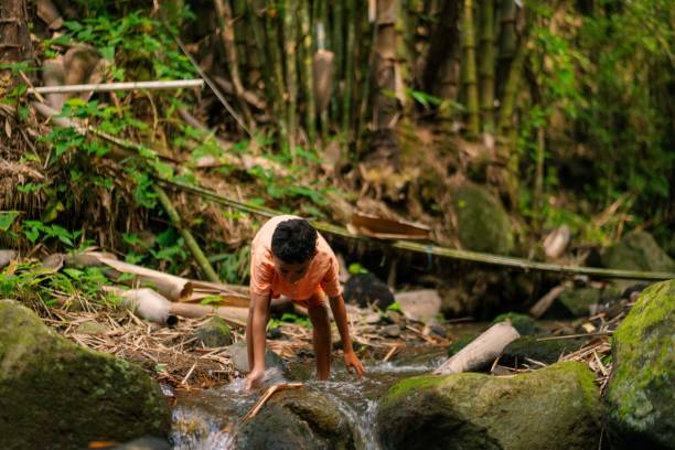istock Pre Adolesence Boy Playing in Shallow River 2161936165