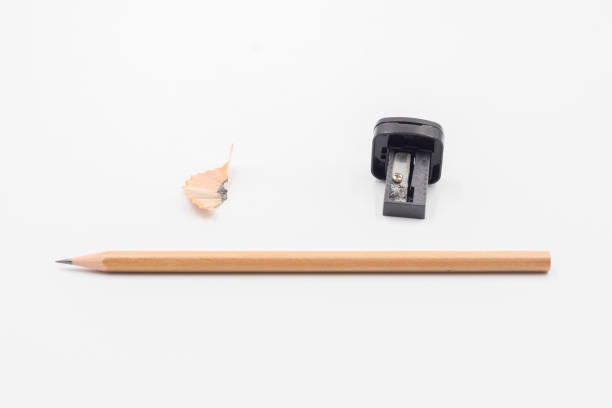 Pencil wooden shavings and colorful crumbs of graphite isolated on orange background. Top view. Flat lay. Creative minimal concept.