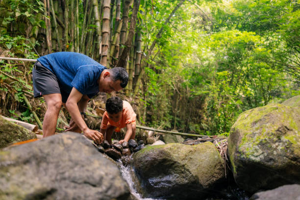 istock Father Pre Adolesence Boy Playing in Shallow River Building Rock Dam 2161938664