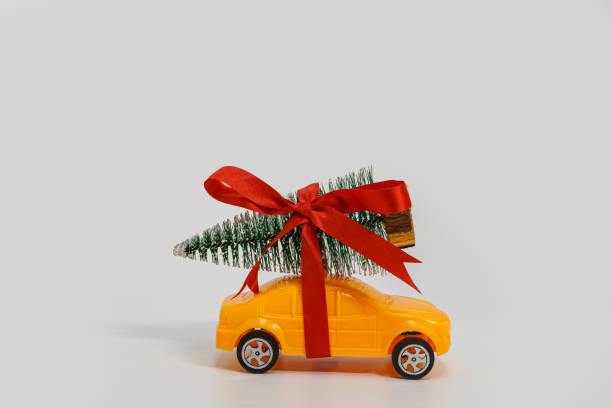 istock Christmas tree with the bow tie on toy yellow car. 2161942935