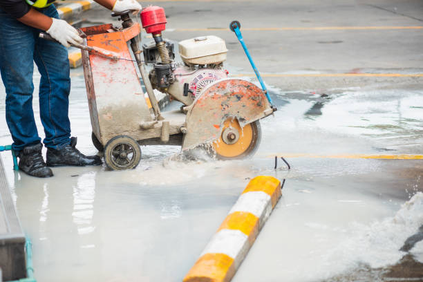 istock A construction worker is using a concrete saw to cut through a wet concrete surface. Workers wear protective gloves and boots. A saw is a large machine that runs on gasoline and has a circular blade. 2161943203