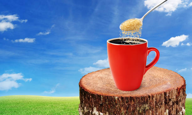 Close-Up Of Sugar Cubes In Spoon Over Tea Cup Against Blue Background