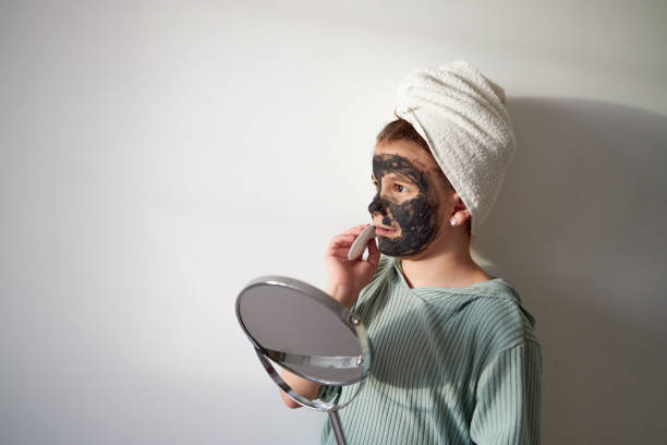 Cheerful girl smiling and enjoying being older wearing moisturizing mask on her face.