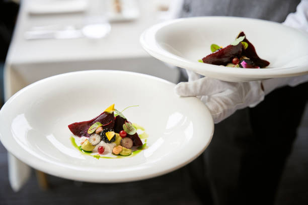 Close up of chef or waiter holding plates with salads in restaurant. Gourmet preparation, service concept