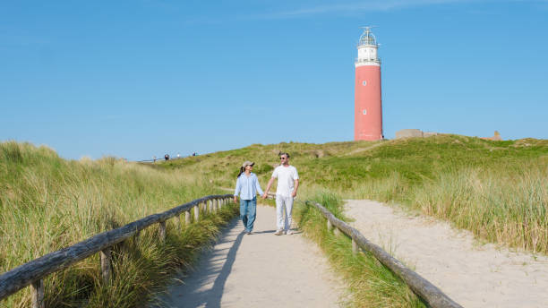 istock A serene scene unfolds as two individuals leisurely walk along a path near a towering lighthouse in Texel, Netherlands 2161953403