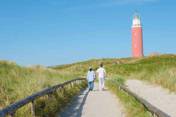 istock Two people strolling along a winding path next to a historic lighthouse on the picturesque island of Texel, Netherlands 2161953438