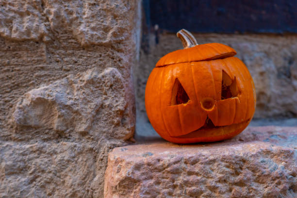 istock A pumpkin with a scary face is sitting on a stone wall 2161954207