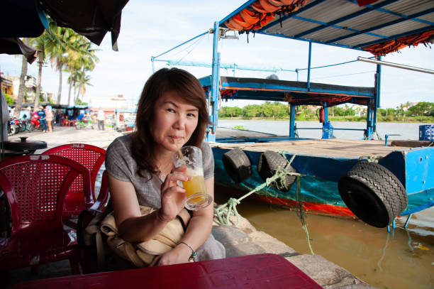 A female tourist refreshes herself with a cold Sugarcane juice while exploring the traditional trading port of Hoi An, Vietnam.