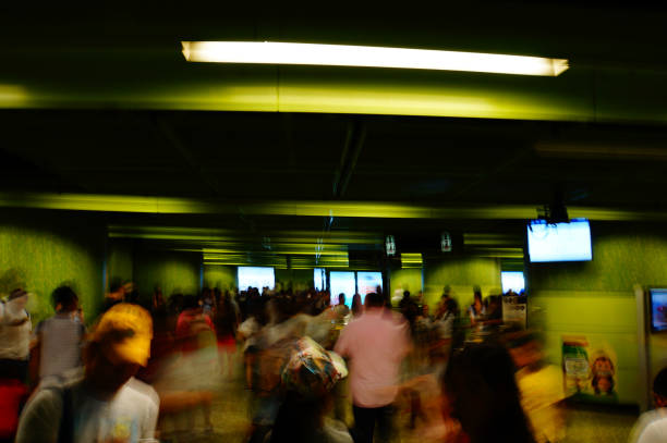 A crowd of people walks through a brightly lit green interior dynamic movement of shutter speed