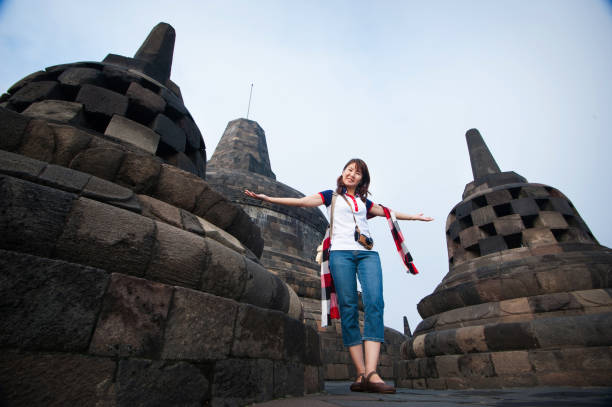 A female Asian tourist with scarf, explores the historic Borobudur, the largest Buddhist temple compound in the world at central Java, Indonesia.