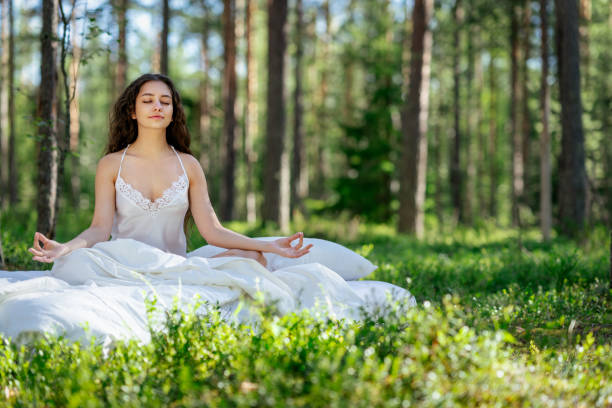 istock Young woman is sitting in the forest on a white bed 2161959921