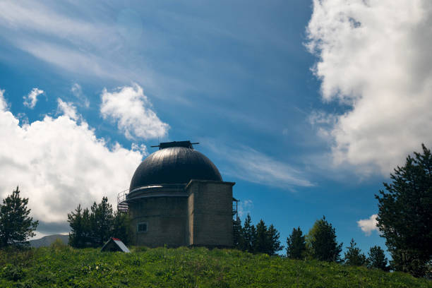 istock Brick observatory dome on grassy hill with cloudy sky. 2161963201