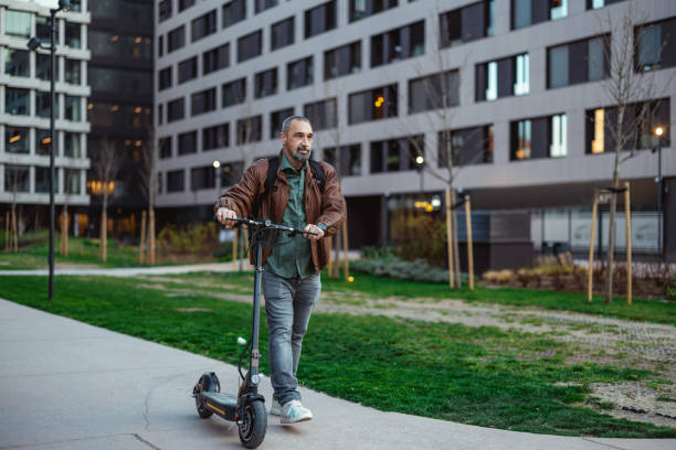 Man walking outdoors alongside electric scooter