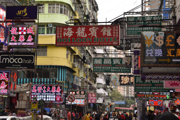 Hong Kong, China - February 5, 2019: A busy street scene in Hong Kong with people walking under advertising hoardings and neon signs.