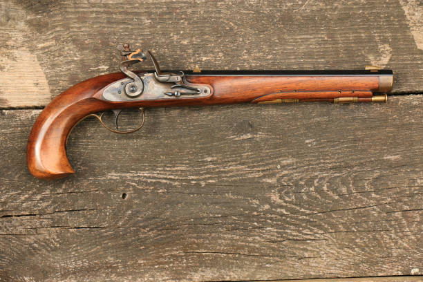 istock Flintlock Kentucky pistol on an old, damaged board. 2161976020