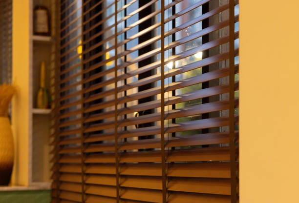 A window with wooden blinds is open, letting in the sunlight. The room has a warm and inviting atmosphere