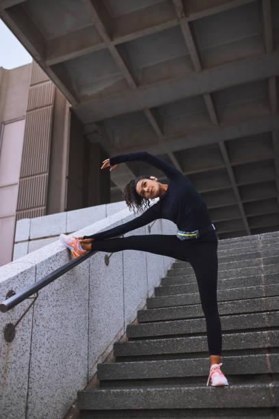 istock Low angle view of young  female athlete warming up and stretching before workout on staircase 2161977032
