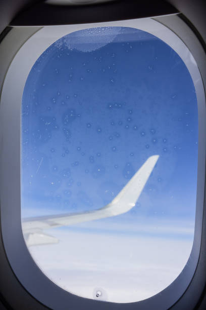 istock View from an airplane window to the wing and clouds, the window on the foreground 2161978209