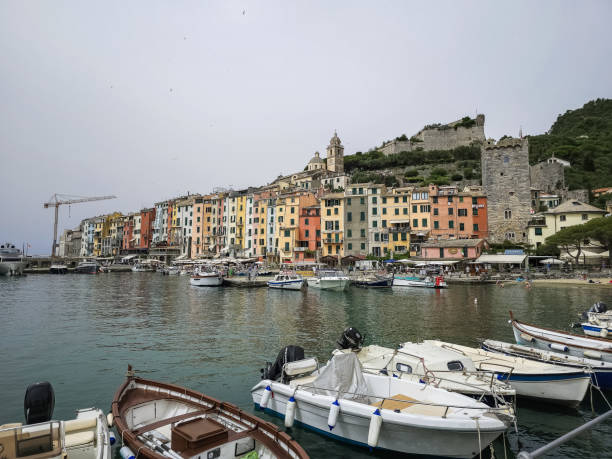 Portovenere with small boats and colorful buildings on a cloudy day.