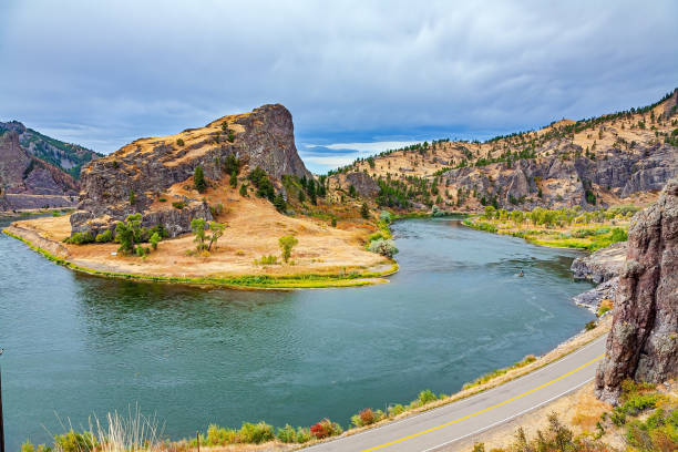 The bed of the deep river bends picturesquely into the hilly banks. Great Missouri River. Asphalt highway runs along the river. Cloudy autumn day. Trip to America