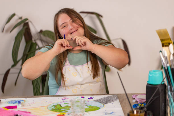 istock Girl with Down Syndrome Making Heart Gesture 2161991179