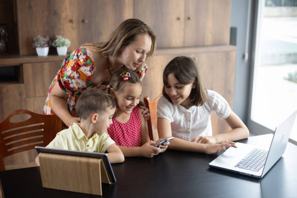 istock Mother and three children using laptop computer, digital tablet and smartphone at home 2161993640