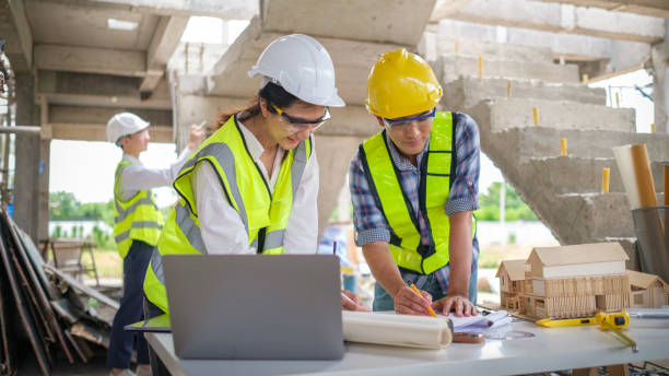 istock Engineers and architects in safety helmet working with blueprints and discussing project at construction site. 2161995903